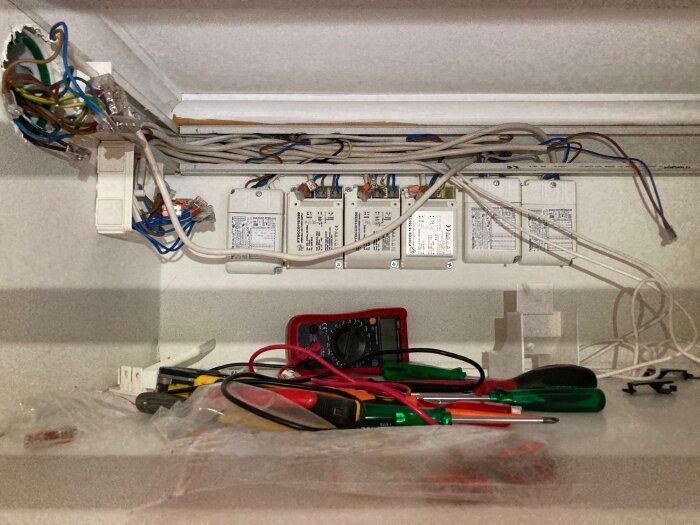 Kabelkanal med LED-drivdon, blandad dubbelisolerad och lågvoltskabel, verktyg samt multimeter; del av belysningsinstallation i diskussionsprojekt.