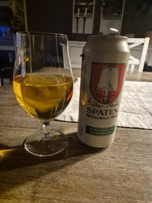 En ölburk av märket Spaten Münchner Hell och ett glas öl på ett bord.