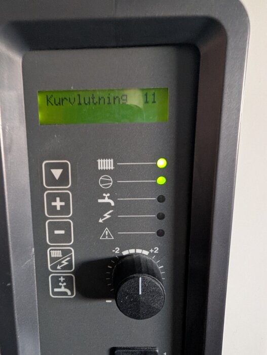 Värmepumpens kontrollpanel med display som visar "Kurvlutning 11" och indikatorlampor som lyser grönt samt inställningsvred.