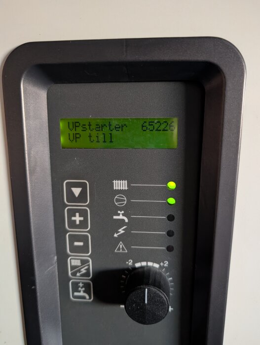 Kontrollpanel för värmepump med grön skärm som visar "VPstarter 65226", med knappar och ratt för inställningar.