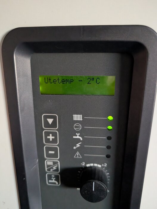 Digital display på värmepump visar "Utetemp -2°C", med kontrollpanel och lysdioder.