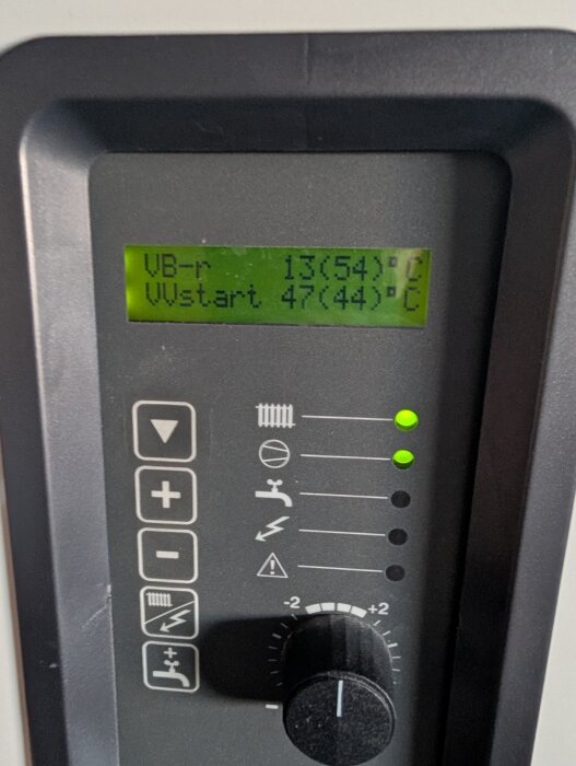 Kontrollpanel av en värmepump med digital skärm som visar temperaturinställningar och gröna indikatorlampor.