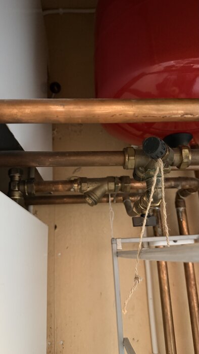 Kopparrör och ventil kopplade till värmepump, med en kran och snöre synligt, eventuellt smutsfilter i ventilationskonstruktion.
