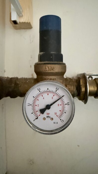 Manometer med skala för bar och MPa monterad på rörsystem, synlig mätare visar tryck.