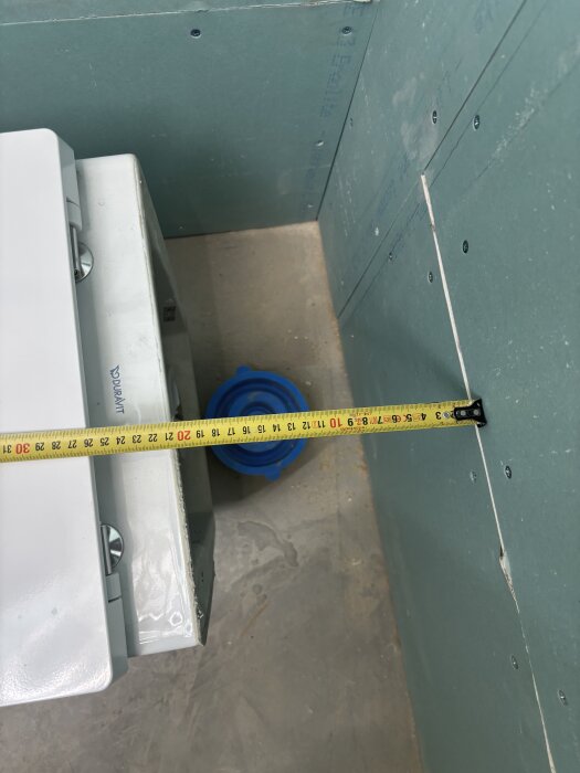 Mästock mot fixtur och vägg i byggprojekt, mätning visar utbyggnadens längd.