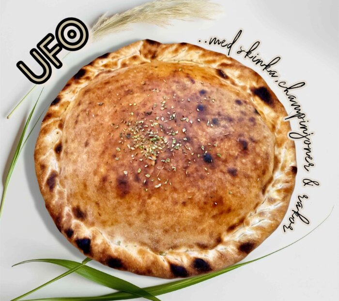 UFO-format pizza med fyllning av skinka, räkor och champinjoner, garnerad med örter.