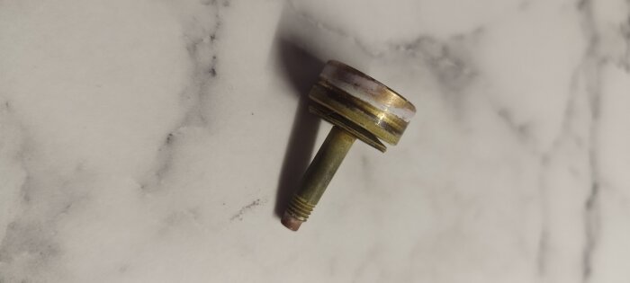 Backventil till blandare av fabrikatet Mora, sent 80-tal, av metall med gängad bas och sliten yta på marmorbakgrund.