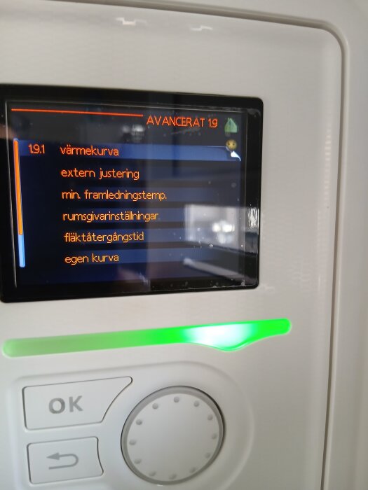 Värmepumpskontrollpanel med display som visar "Avancerat 1.9" och inställningar för värmekurva, extern justering och fläktåtergångstid.
