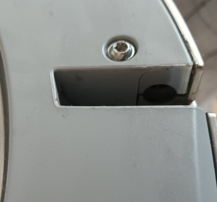 Gångjärnsinfästning på en Bosch tvättmaskinslucka, närbild som visar skruv och plastdetaljer, med slitage eller skador vid fästen.