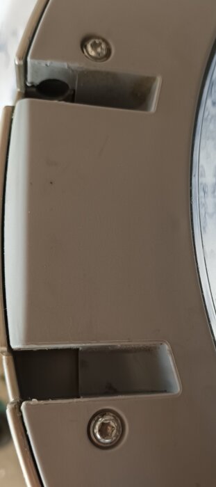 Närbild på tvättmaskinslucka av märket Bosch, Serie 2, med fokus på gångjärnsområdet. Skruvar och plaststruktur synliga.