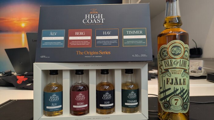 Fyra miniatyrflaskor av High Coast Whisky och en flaska Isle of Lime Gotländsk whiskey Fjäle visas på ett bord.
