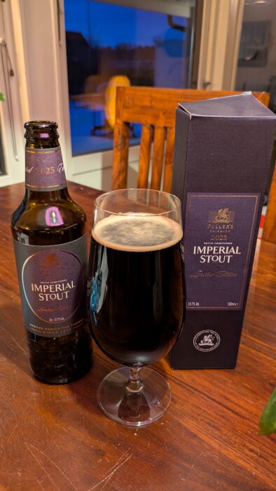Flaska och glas med Imperial Stout på ett bord, bredvid kartongförpackning i träinteriör.