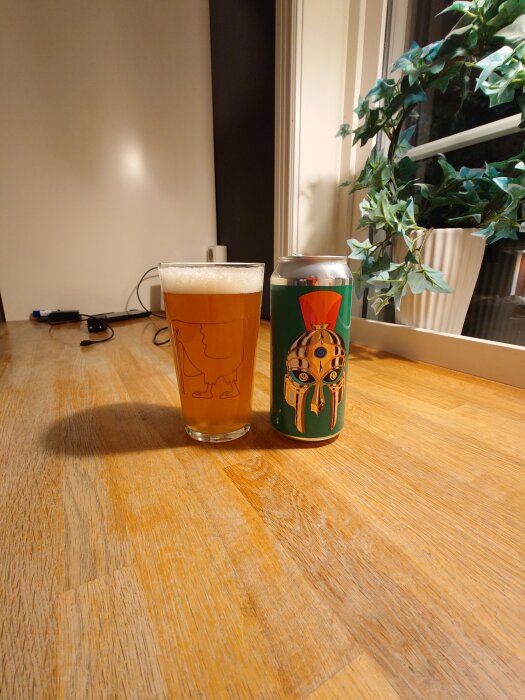 Ölglas med bärnstensfärgad dryck bredvid en burk med hjälmmotiv på ett träbord, växt i bakgrunden.