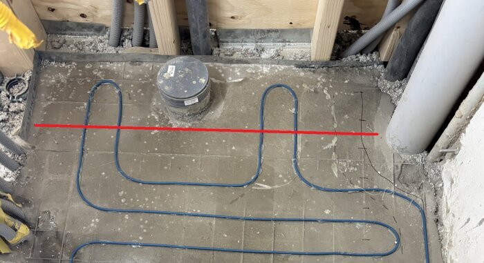Under construction floor with exposed blue heating cables and a red line indicating area of concern.