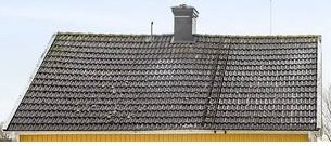 Gammalt tak med tegelpannor och en skorsten, taket ser lite böjt ut i mitten.