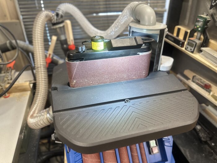 Kombinerad band/spindelslip Scheppach OSM600 med sugkoppling och slipband i verkstadsmiljö.