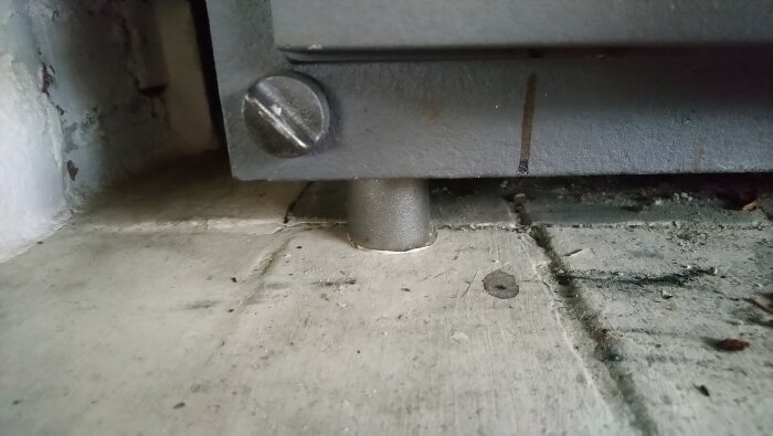 Närbild av en braskamins stödben som verkar luta åt sidan, med tecken på rörelse på golvet.