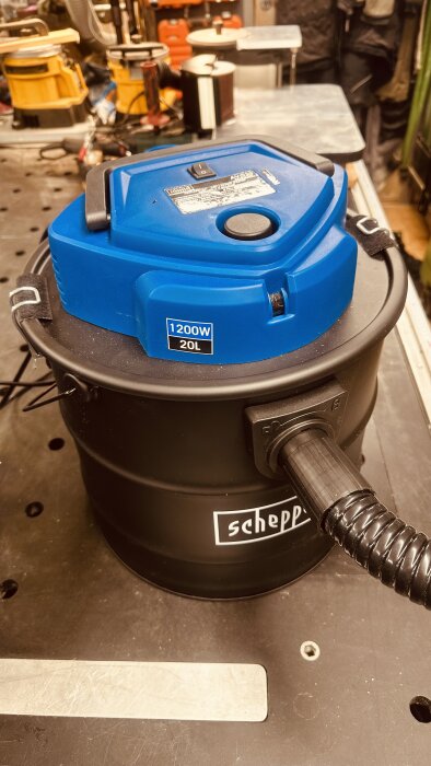 Scheppach asksug AVC20 med 1200W motor och blått lock fotograferad i en verkstadsmiljö.