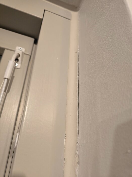 Bilden visar en närbild av en balkongdörr där fogen eller silikonen mellan ramen och väggen ser ut att ha släppt.