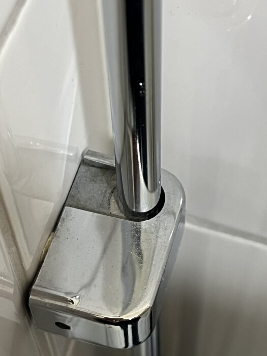 Silverfärgat väggfäste för vattenrör i badrum, som verkar bestå av två delar som går att isärta.