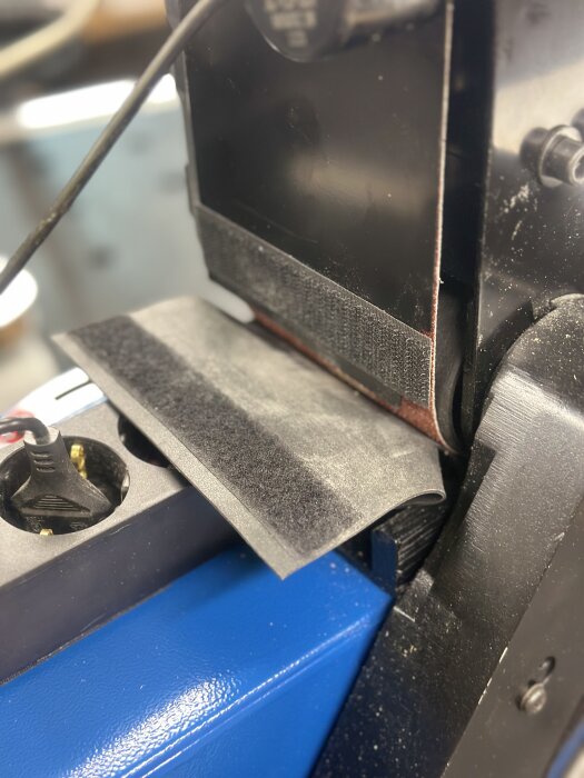 Scheppach bandslip BTS900 med slipaggregatet uppfällt i 90˚ vinkel, delar av aluminiumstomme och slipbord synliga, för renoveringsprojekt.