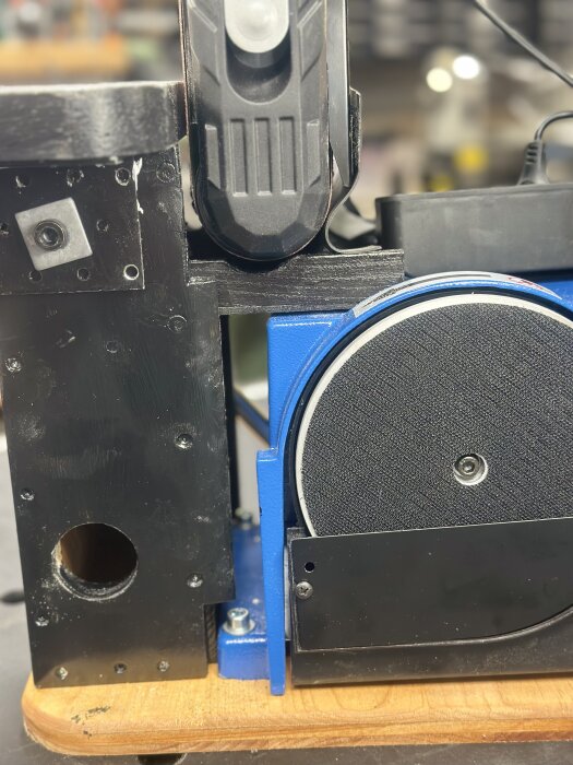 Scheppach band och tallriksslip BTS900 med gjuten aluminiumstomme, omgiven av svarta och blå detaljer, står på en träyta i en verkstadsmiljö.
