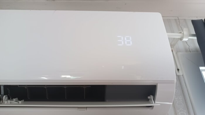 Väggmonterad luftvärmepump med digital temperaturdisplay som visar siffran 38.