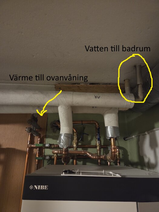 Rörsystem i källare med märkningar för värme och vatten till badrum, centralvärmeanläggning och ledningar synliga.