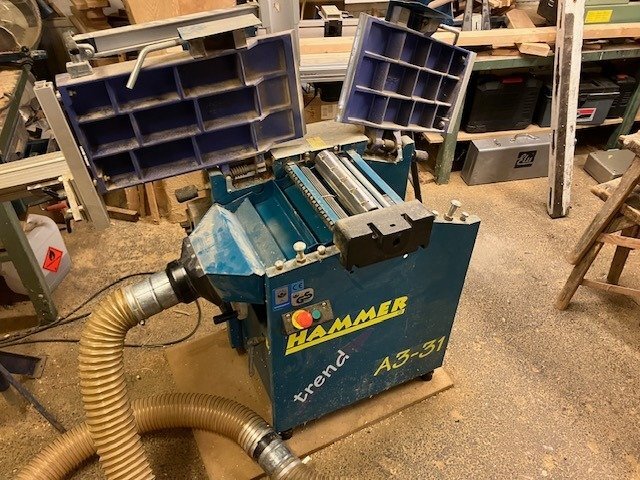Hammer A3-31 rikt- och planhyvel i en snickeriverkstad, omgiven av trä och verktyg, fotograferad inför försäljning.