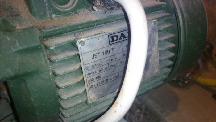 Bild på en grön vattenpump med en metallplatta där det står "DAB JET 100 T" och tekniska specifikationer.