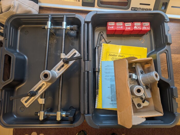 Fräsjigg för låskistor i en plastlåda, med tillbehör och instruktioner från Souber Tools, samt röda borradaptrar märkta för trä och aluminium.