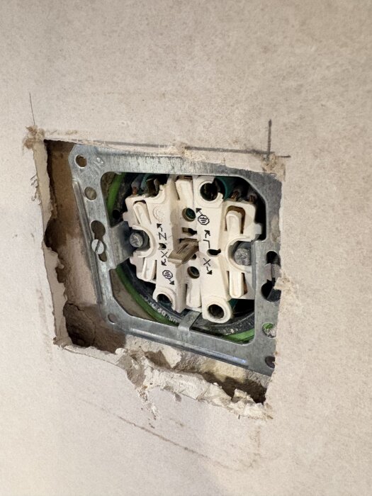 Eluttag i kök med skavanker i gipsskivan runt omkring, monterat för djupt efter renovering.
