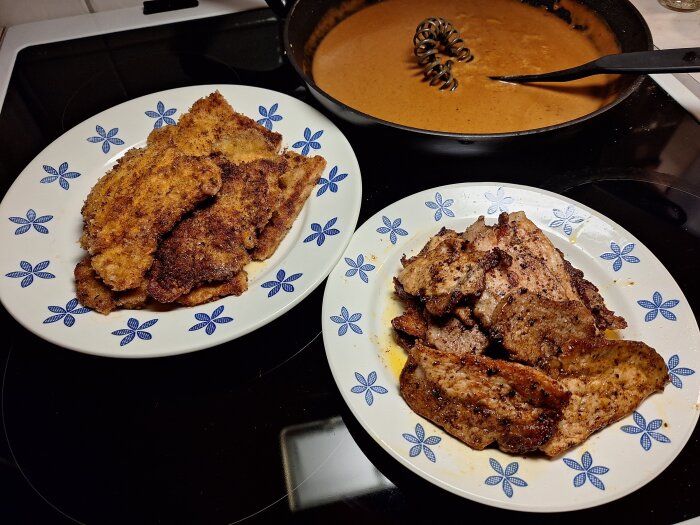 Två tallrikar med panerad schnitzel och kryddade fläskytterfiléskivor, samt stekpanna med sås i bakgrunden.