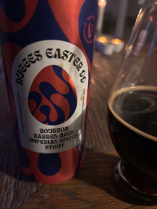 Burk med Dugges Easter 99 Bourbon Barrel Aged Imperial Spices Stout och ett glas med stout på ett träbord.