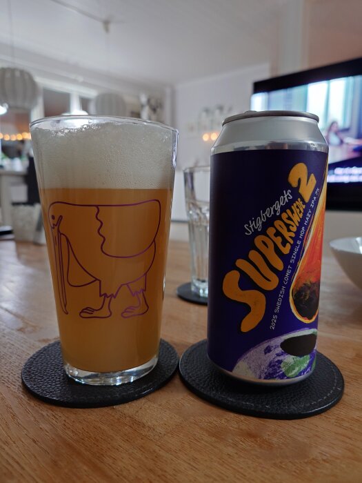 En ölglas fyllt med skummande öl bredvid en burk med etiketten "Stigbergets SUPERSWEEE 2" på ett bord.