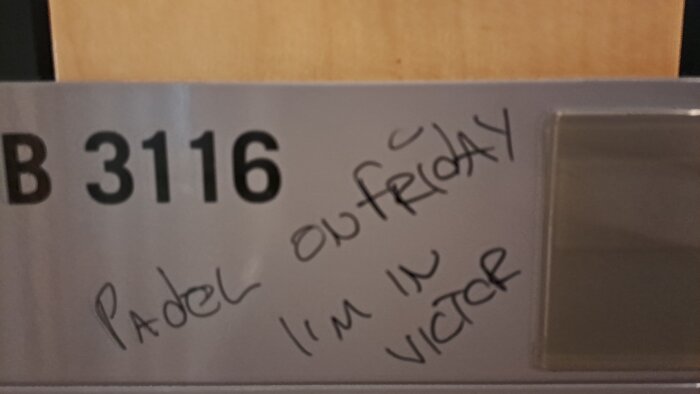 Dörrskylt med numret B 3116 och handskrivet meddelande om padel på fredag samt text "I'm in Victor".