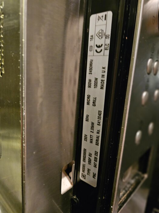 Etikett på en Electrolux mikrovågsugn med teknisk information, modell- och serienummer synlig vid dörren.