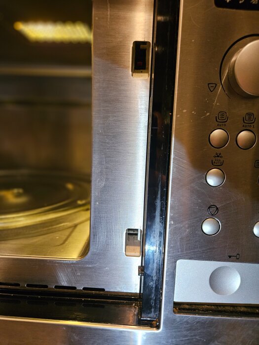 Mikrovågsugn med öppen dörr, visande låsmekanismen och kontrollpanelen, problem med fastande öppningsknapp, Electrolux-modell.
