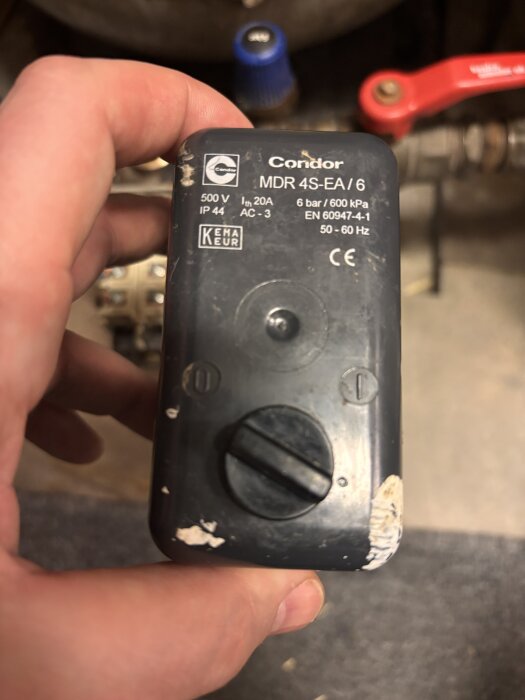 Tryckströmbrytare Condor MDR 4 S/6 i en persons hand, med information om spänning och tryck synlig på framsidan.