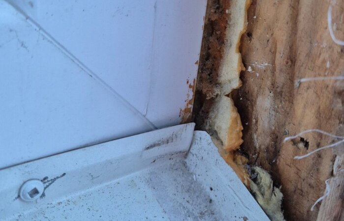 Gap between metal window sill and wooden trim with insulation visible, indicating improper installation not meeting Swedish standards.