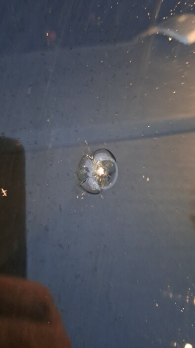Stenskott i bilens vindruta som orsakat en spricka.