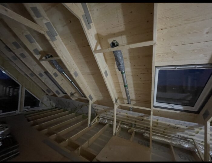 Ventilationssystem för tilluft i ett rum under tak med synliga rör och fönster.