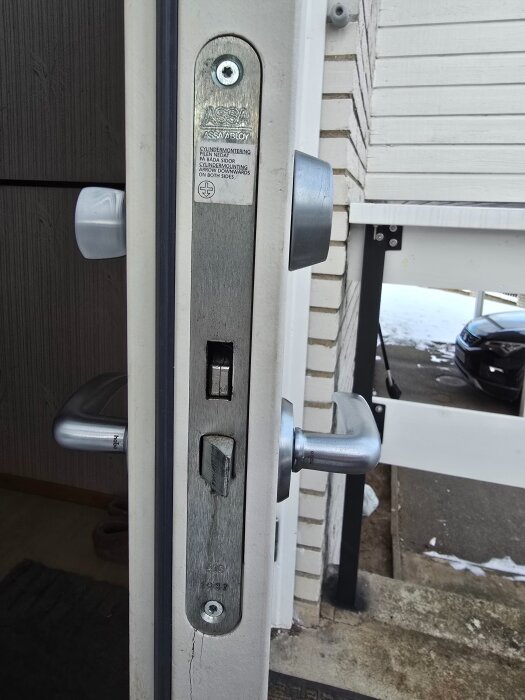 Låshus Assa 410 monterat i en dörr, sedd från sidan, med synliga dörrhandtag på båda sidor och en skylt med text "ASSA ABLOY".