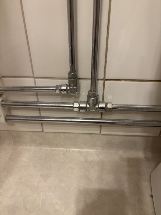 Rör och kopplingar vid en handdukstork i ett 1990-tals lägenhetshus, kopplad till tappvarmvattnet, men blir inte varm.