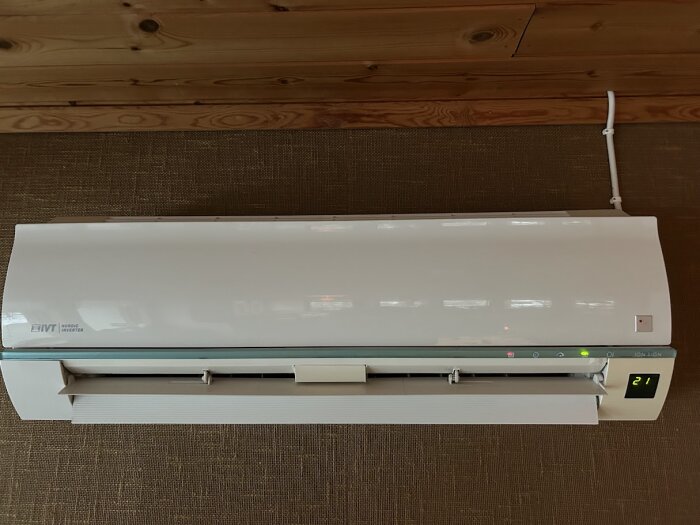 Luftvärmepump IVT Nordic Inverter monterad på en trävägg, inställd på 21 grader.