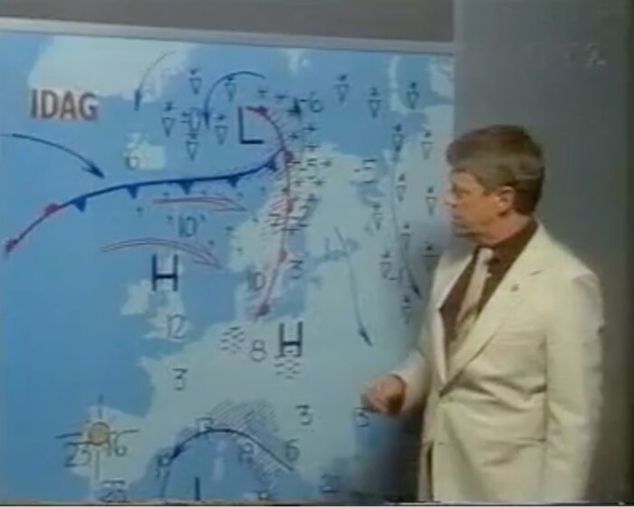En person i vit kostym presenterar en väderkarta med lågtryck, högtryck och fronter markerade över norra Europa.