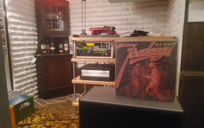 Vinylskiva med ZZ Tops "Fandango!" på ett hyllplan med ljudutrustning, omgivna av en retro inredning.