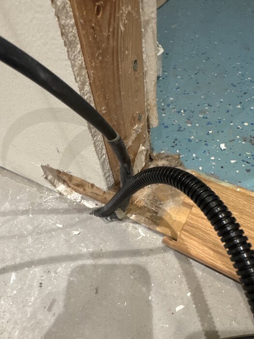 Skarv mellan svart värmekabel och 230V-kabel synlig ovanför spacklat golv nära termostat i hörn av rummet.