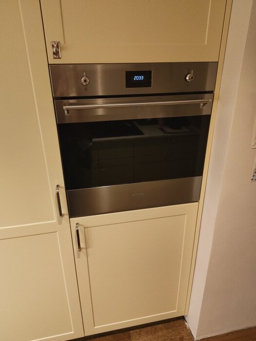 Inbyggd ugn monterad i modifierad IKEA-högskåpsstomme ovanför frys, anpassad för bättre funktion och ventilation i köket.