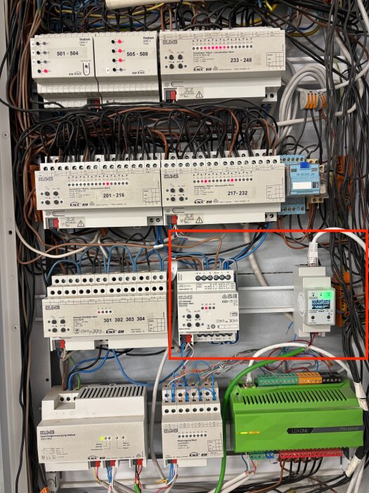 Elcentral med olika KNX komponenter och kablage, inkluderande säkringsmoduler och en grön Loxone Miniserver, markerade sektioner med kabelanslutningar.